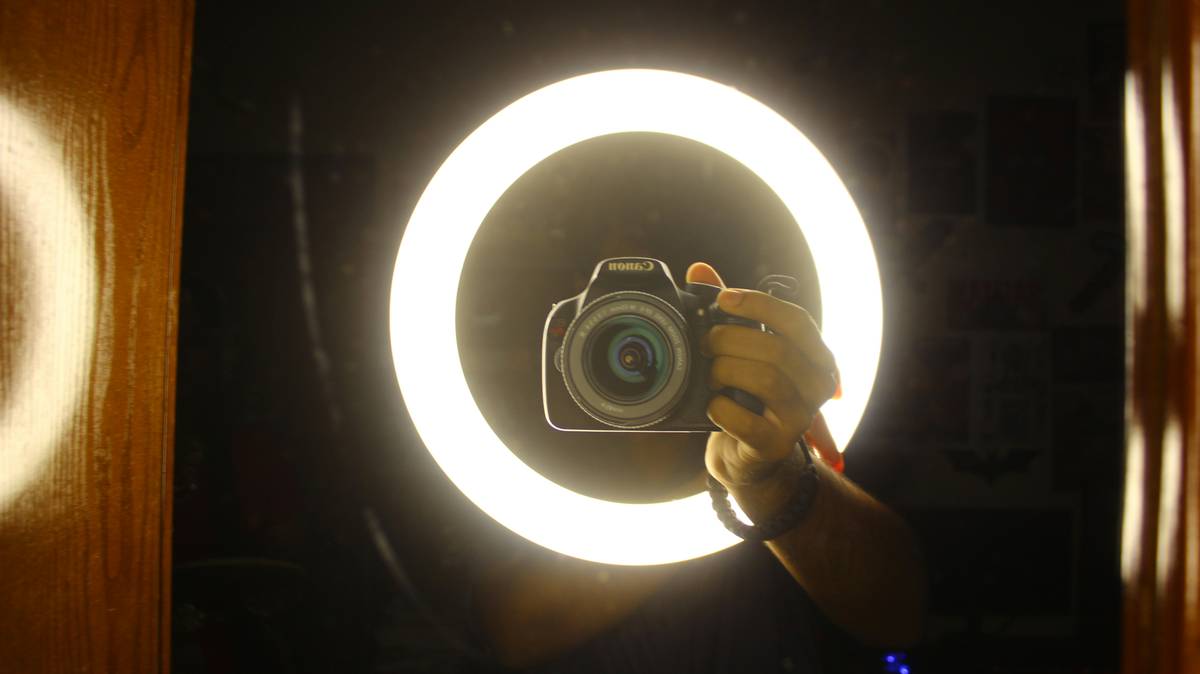 Gamer adjusting ring light with on-screen tutorial showing content creation light how to change settings