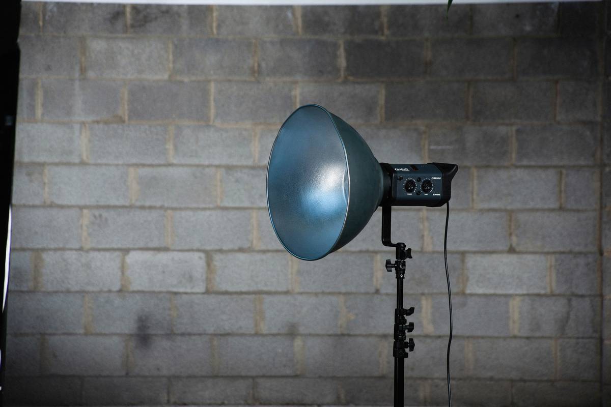 studio light stand boom holding a softbox light above a gaming desk setup
